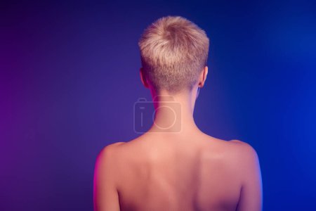 Téléchargez les photos : Arrière colonne vertébrale vue photo de fille avec cheveux courts pixie coiffure sur dégradé fond de couleur ultraviolette. - en image libre de droit
