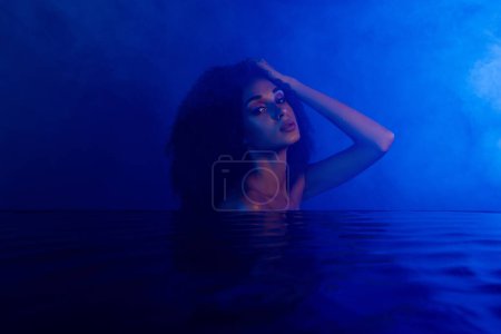 Foto de Foto de impresionante dama tentadora disfrutando de la higiene del baño nocturno aislada sobre fondo ultravioleta oscuro. - Imagen libre de derechos