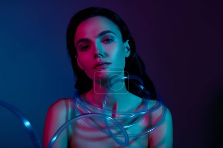 Foto de Foto de mujer con atado en el cuello cables de belleza de plástico aislados sobre el gradiente de neón fondo de color oscuro. - Imagen libre de derechos