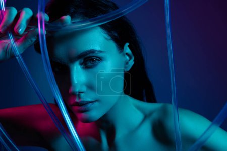 Foto de Foto de mujer toque plástico belleza cable mirada en la cámara aislado ultravioleta neón color fondo. - Imagen libre de derechos