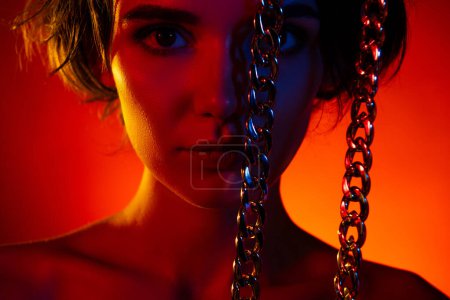 Photo for Photo of adorable cool woman naked shoulders rising golden chain isolated red neon color background. - Royalty Free Image