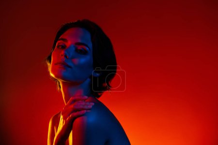 Photo for Photo of stunning shiny woman naked shoulders dressed applying body balm empty space isolated red neon color background. - Royalty Free Image