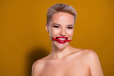 Foto de Foto de mujer sonriente mordedura de dientes chile rojo aislado color amarillo mostaza fondo. - Imagen libre de derechos