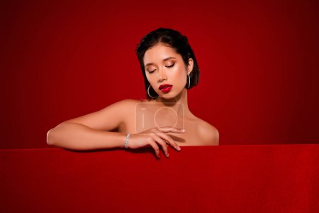 Photo for Photo of attractive chinese young woman sexy model look down empty space shoulders off isolated on red color background. - Royalty Free Image