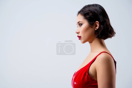 Téléchargez les photos : Photo de profil magnifique jeune fille regarder espace vide habillé vêtements en cuir rouge isolé sur fond gris clair. - en image libre de droit