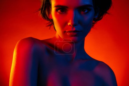 Foto de Foto de mujer hermosa seductora hombros desnudos sonriendo burlas aisladas fondo de color rojo neón. - Imagen libre de derechos