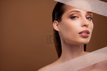 Photo for Photo of shiny pretty woman nude shoulders using kinesio tapes empty space isolated beige color background. - Royalty Free Image