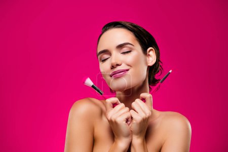 Téléchargez les photos : Portrait photo de jolie jeune femme profiter brosse de maquillage visage épaules off isolé sur fond de couleur rose. - en image libre de droit