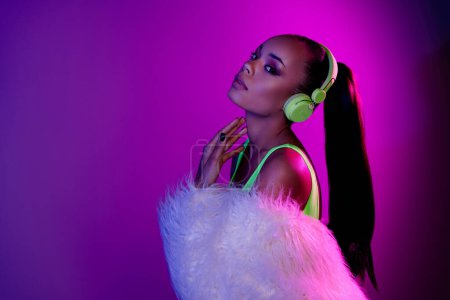 Photo of shiny adorable lady dressed fur coat headphones enjoy melody empty space isolated purple color background.