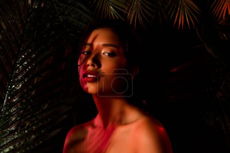 Photo for Photo of chinese japanese girl under orange lights stand near dark palm exotic trees. - Royalty Free Image