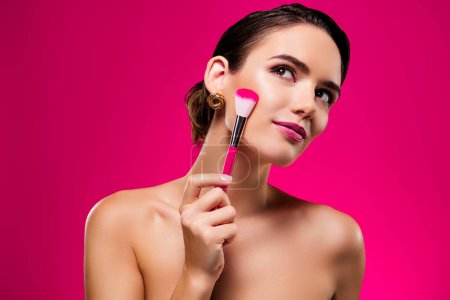 Téléchargez les photos : Portrait photo de jolie jeune femme appliquer brosse visage vide espace épaules off isolé sur fond de couleur rose. - en image libre de droit