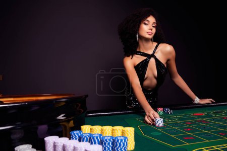 Téléchargez les photos : Photo de fille attrayante en robe de cocktail jouer au poker dans las vegas club pari chance holdem pour gagner des millions de dollars. - en image libre de droit