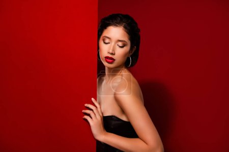 Foto de Foto de la hermosa mujer coreana aspecto banner pared vestido de cuero negro prenda aislada en el fondo de color rojo. - Imagen libre de derechos
