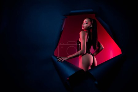 Photo of african american girl in hole torn wall stand back rear view isolated dark neon background.