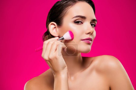 Téléchargez les photos : Portrait photo de jolie jeune femme appliquer brosse visage épaules off isolé sur fond de couleur rose. - en image libre de droit
