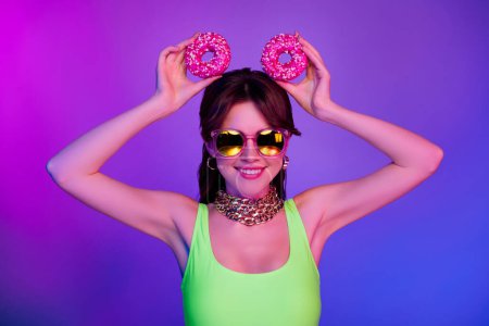 Téléchargez les photos : Photo de joyeuse fille souriante tenir deux biscuits glacés sur la tête isolé fond de couleur ultraviolette. - en image libre de droit