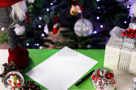 Foto de Una hoja de papel sobre la mesa para una carta de Santa con deseos en el fondo de un árbol de Navidad. Ambiente de Navidad y Año Nuevo. Concepto de una infancia feliz. - Imagen libre de derechos
