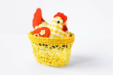Foto de Decorative chicken in a yellow wicker basket on a white isolated background with space for text. Easter card Provence. Easter composition. - Imagen libre de derechos