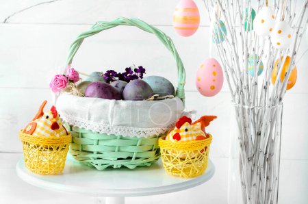Foto de Easter eggs in a wicker basket on a white background. Decorative chicken with eggs. Easter tree. Easter composition with space for text. - Imagen libre de derechos