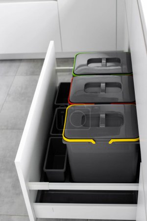 Colorful bins for sorting of plastic, paper garbage and organic waste at home. Modern kitchen with a system for sorting waste. Waste Separation Concept. Zero waste. Eco-friendly. Vertical photo.