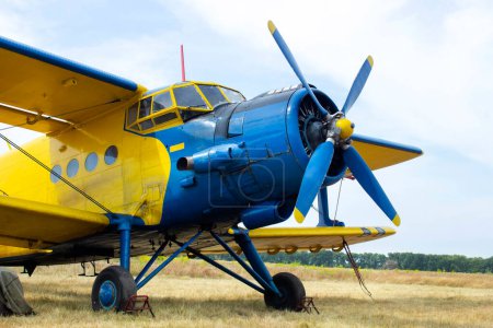 Primer plano de un pequeño plano amarillo-azul de pie en un campo. Avión de hélice viejo primer plano.