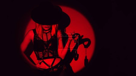 Photo for Sexy slave girl in underwear and a hat holds handcuffs in hands. Concept of BDSM submissive woman - Royalty Free Image
