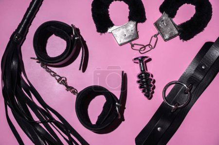 Photo for Set of adult erotic toys for BDSM sex with submission and domination. Flogger whip, handcuffs and butt plug on pink background - Royalty Free Image