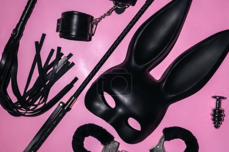 Téléchargez les photos : Handcuffs, whip flogger for BDSM sex with submission and domination. A set of adult intimate erotic sex toys on a pink background - en image libre de droit