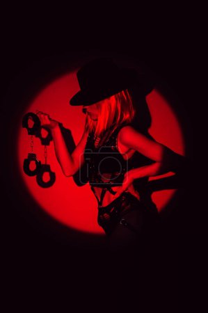 Photo for Sexy slave girl in underwear and a hat holds handcuffs in hands. Concept of BDSM submissive woman - Royalty Free Image