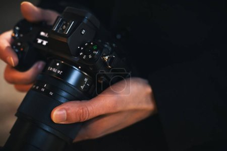 Foto de Fotógrafo sostiene una moderna cámara sin espejo en las manos de cerca - Imagen libre de derechos