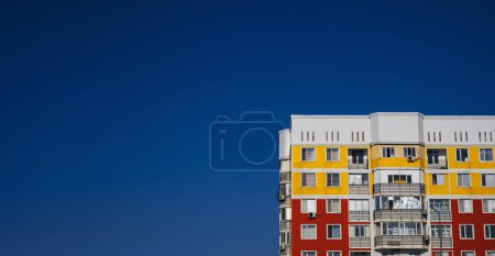 Téléchargez les photos : Maison neuve résidentielle avec fenêtres et balcons sur fond bleu ciel - en image libre de droit
