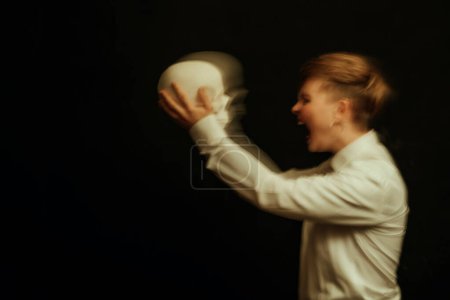 Photo for Psychopath with schizophrenia and mental disorders. Portrait of a girl with a skull in hands on a dark background - Royalty Free Image