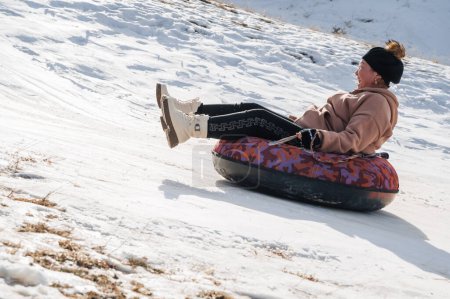 Téléchargez les photos : TAU SAMALY, KAZAKHSTAN - 23 DÉCEMBRE 2023 : les Kazakhs heureux descendent un toboggan en hiver avec de la neige au centre récréatif Tau Samaly au Kazakhstan - en image libre de droit
