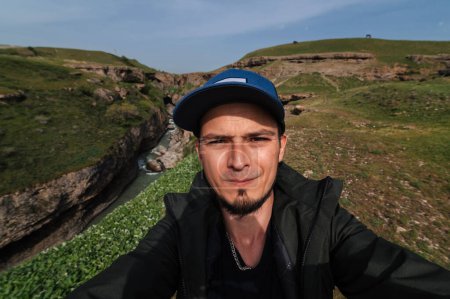 bearded Caucasian male traveler takes a selfie on a smartphone against the background of Aksu Canyon in Kazakhstan in spring