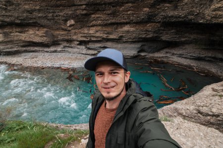 viajero caucásico barbudo toma una selfie en un teléfono inteligente contra el fondo de un río en Aksu Canyon en Kazajstán en primavera