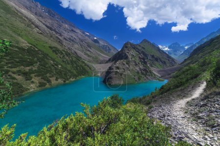 Lago con agua azul clara en las montañas bajo el cielo con nubes en verano