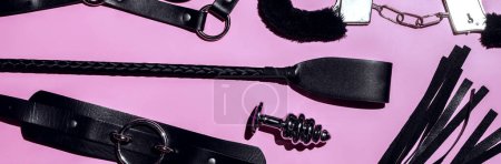 set of BDSM sex toys with handcuffs, whip flogger, butt anal plug for submission and domination on a pink background. Wide header cover for sex shop
