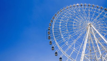 white big Ferris wheel on background a bright blue sky in the amusement park at fair in summer with copy space