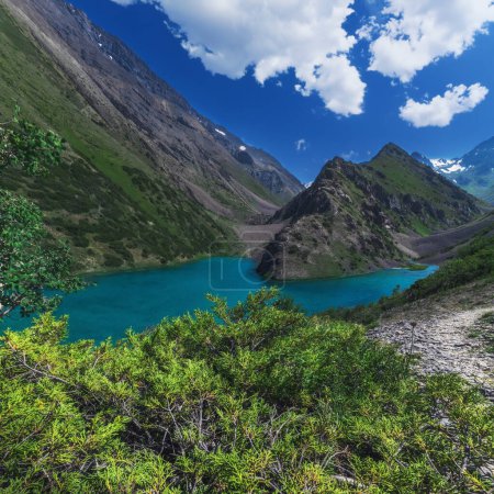 Lake with clear blue water in the mountains under the sky with clouds in summer