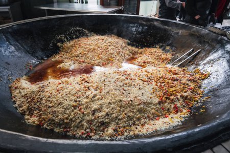 oriental dish of Uzbek cuisine is pilaf in a huge cauldron in the kitchen of an Asian restaurant in Tashkent Pilaf Center in Uzbekistan