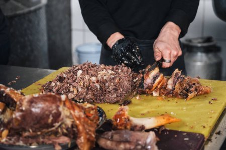 homme chef a coupé de la viande de b?uf bouillie au couteau sur une planche à découper dans la cuisine d'un restaurant à Tachkent en Ouzbékistan