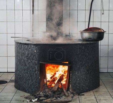 large cauldron on a wood stove with fire for cooking traditional Uzbek pilaf in a restaurant in Uzbekistan