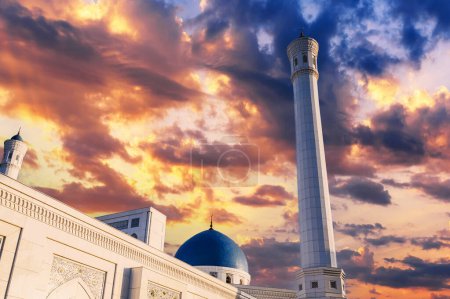 Hohes weißes Minarett und blaue Kuppel der modernen Kleinen Moschee in Taschkent in Usbekistan vor dem Hintergrund des schönen Sonnenuntergangs