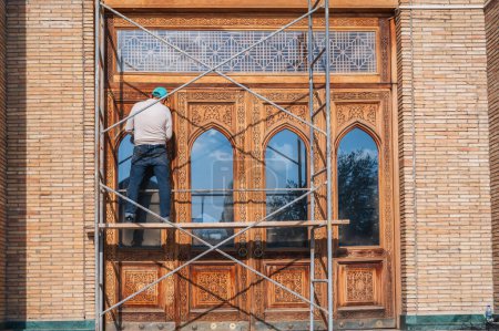 male worker restores an ancient carved wooden door to the Hazrati Imam Mosque in Uzbekistan in Tashkent