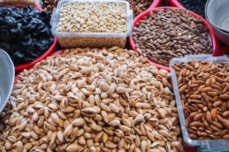 assortment of different variety nuts, dried fruits on counter at oriental Uzbek food bazaar. Almonds and prunes in market stall