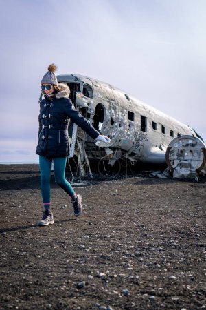 Foto de Mujer caminando junto a un avión naufragado en Islandia - Imagen libre de derechos