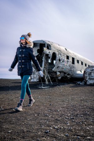 Foto de Mujer caminando junto a un avión naufragado en Islandia - Imagen libre de derechos