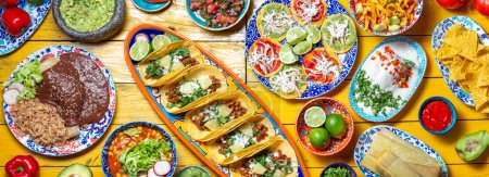 Téléchargez les photos : Nourriture mexicaine festive pour la fête de l'indépendance - Independent chiles en nogada, tacos al pastor, chalupas pozole, tamales, poulet à la sauce mole poblano. Fond jaune - en image libre de droit
