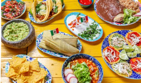 Comida festiva mexicana para el día de la independencia - chiles independientes en nogada, tacos al pastor, chalupas pozole, tamales, pollo con salsa mole poblano. Fondo amarillo
