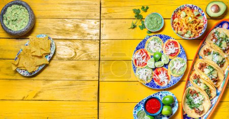 Téléchargez les photos : Nourriture mexicaine festive pour la fête de l'indépendance - Independent chiles en nogada, tacos al pastor, chalupas pozole, tamales, poulet à la sauce mole poblano. Fond jaune - en image libre de droit